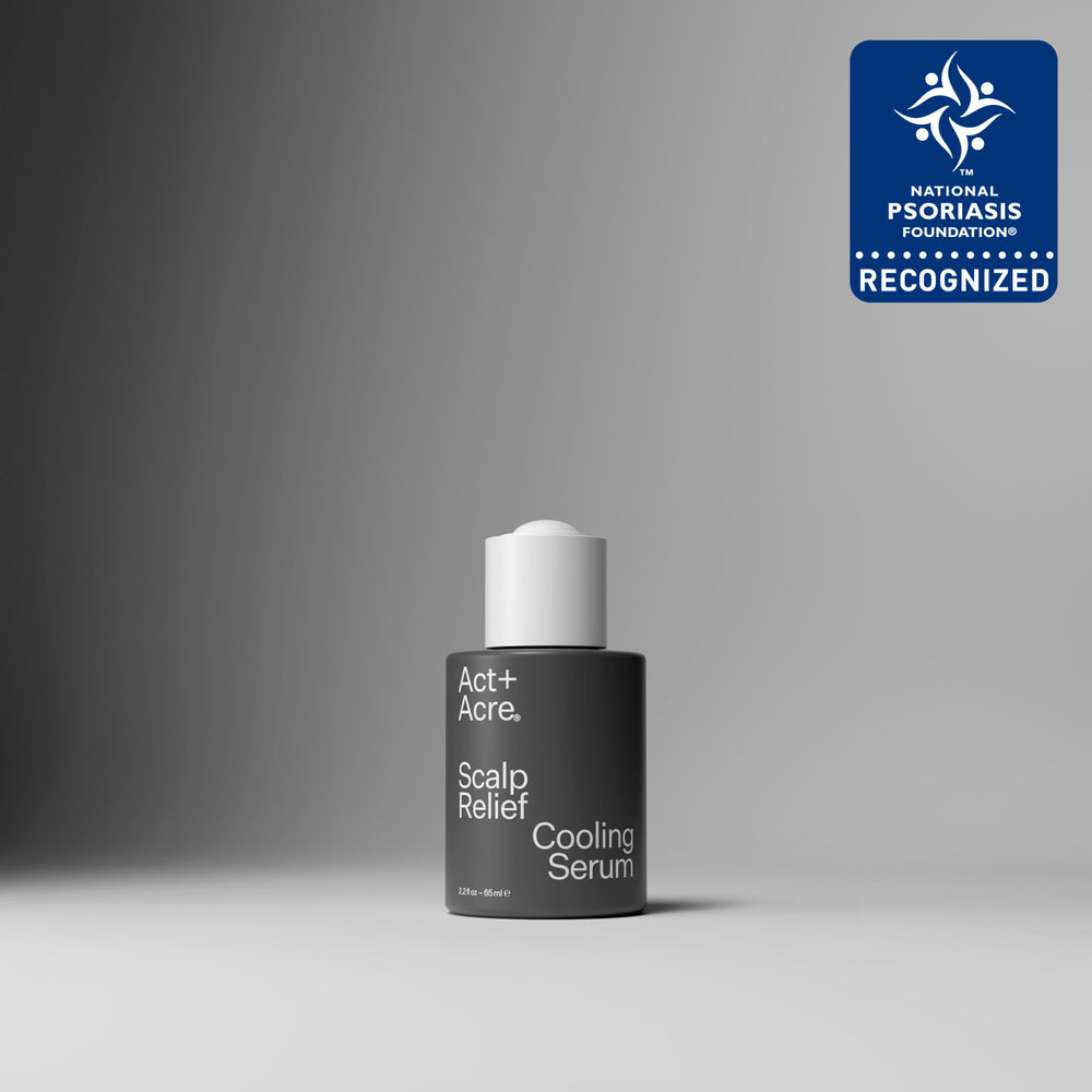 A single bottle of Act+A. Microbiome Cooling Scalp Serum stands centered on a smooth gray studio surface with a dark gray background.